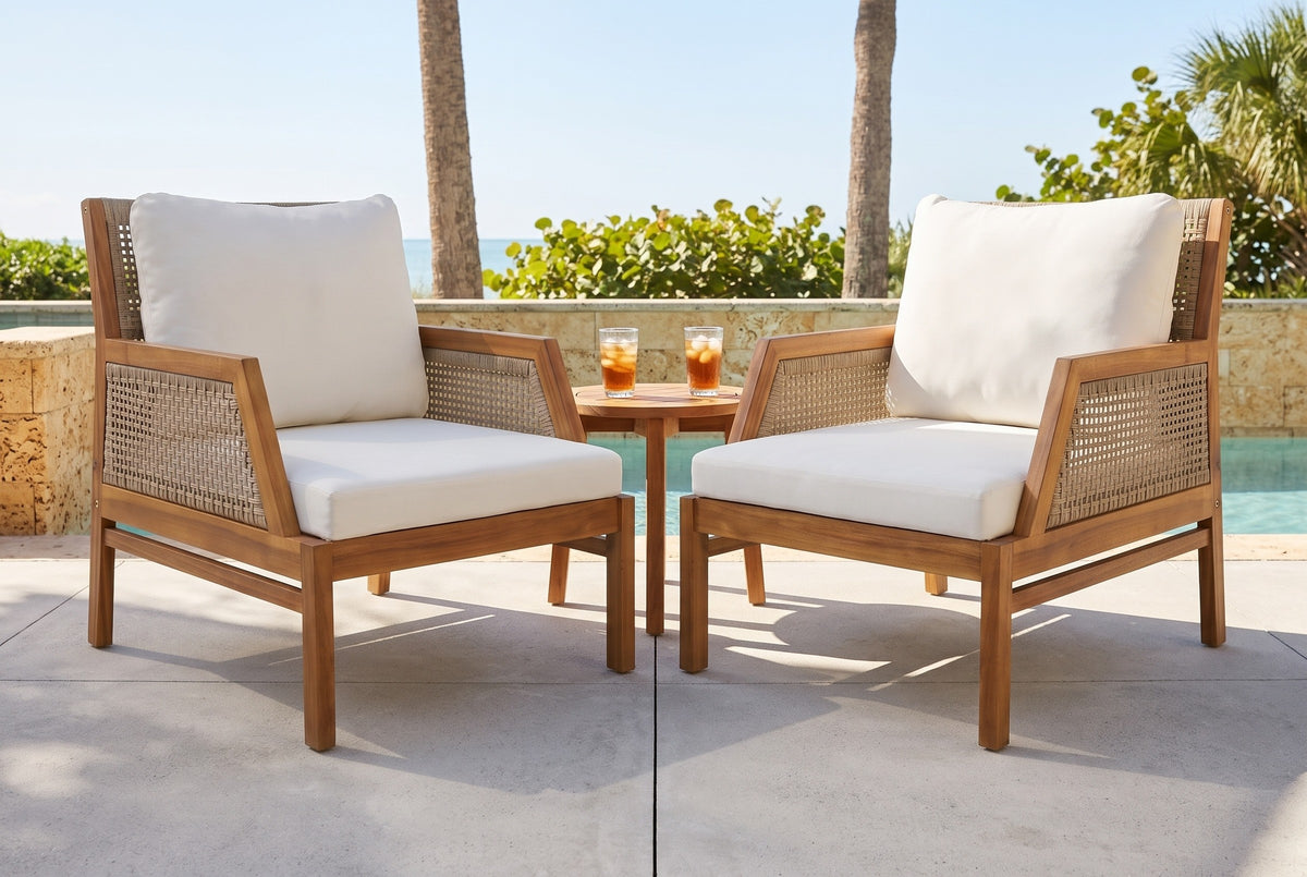 Two Buccheri club chairs on a concrete pool terrace in Sarasota, a honey coquina stone wall, sea grape and palms behind (side table not included)