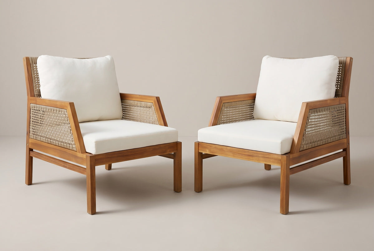 The set of two Buccheri acacia and wicker club chairs with ivory cushions, turned slightly towards each other on a light studio backdrop