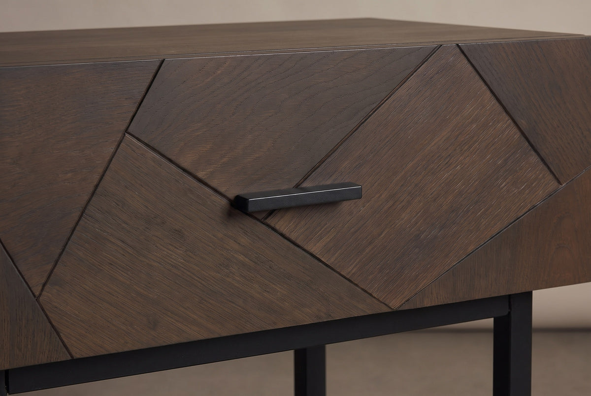 The drawer front of the Budoni nightstand: angled oak pieces with fine dark grooves and one short black bar pull in the middle