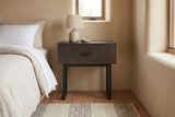 Budoni smoked oak nightstand against a sand-coloured lime plaster wall in a Santa Fe bedroom with a terracotta tile floor and a wool rug