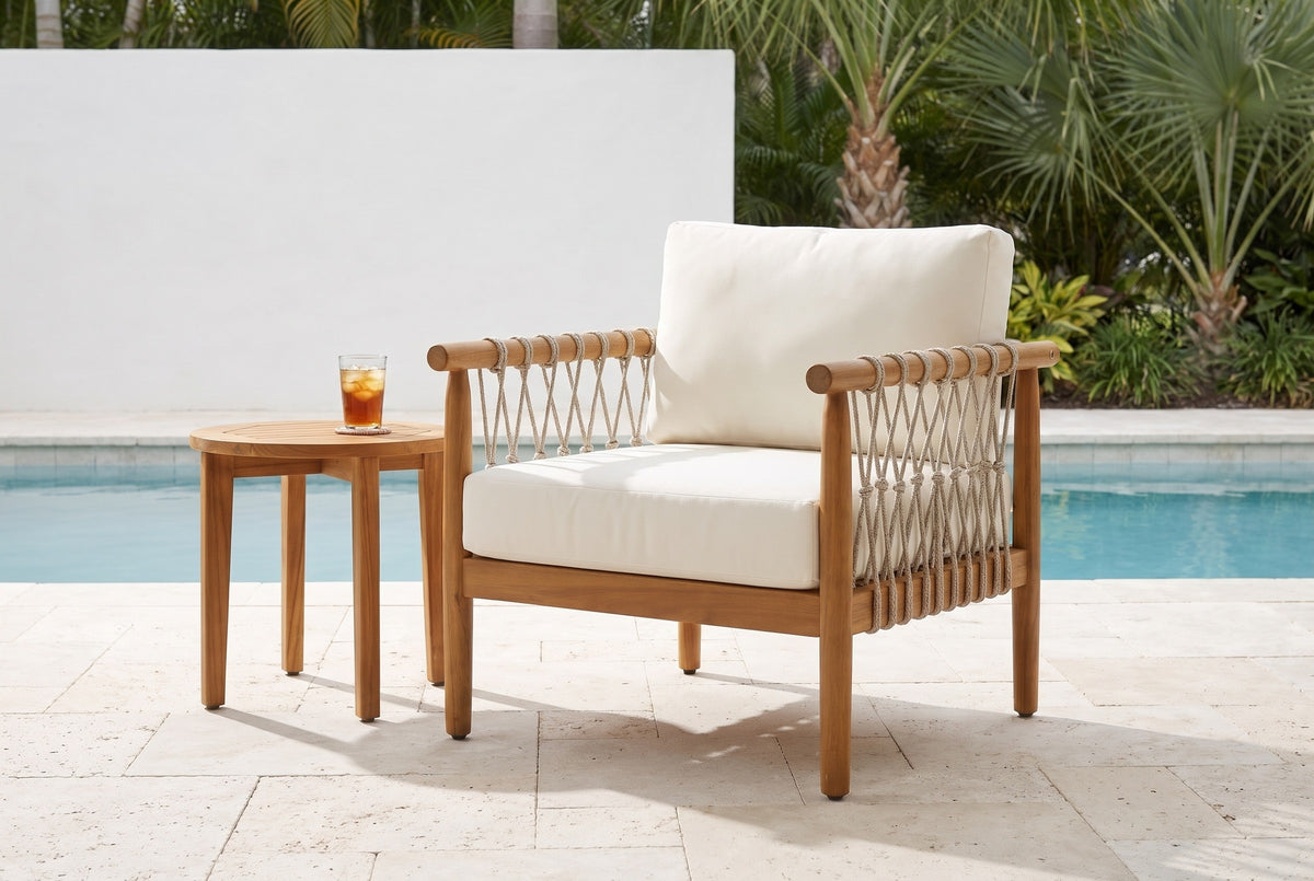Burgio acacia and rope club armchair on pale stone pavers beside a pool at a Sarasota house, a white limewash wall and palms behind (side table and glass not included)