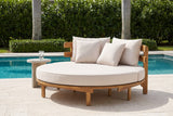 Butera round acacia daybed on a travertine pool terrace in Naples, Florida, a clipped hedge and palms behind (side table not included)