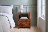 Cabras chestnut mango arch nightstand with a ceramic lamp in a Savannah bedroom with a sage green board-and-batten wall and pale heart-pine floors