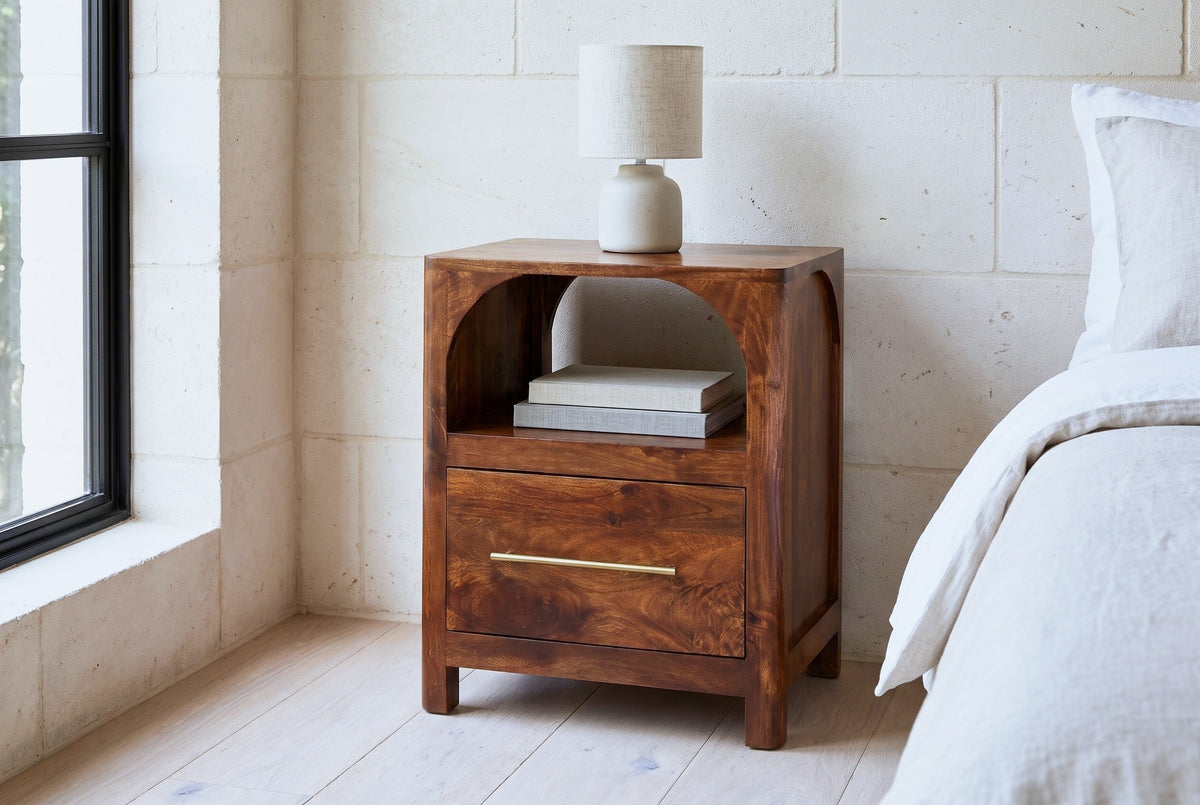 Cabras chestnut mango arch nightstand against a pale cream limestone block wall in a Texas Hill Country bedroom with a bleached oak floor