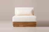 A Calamosche club chair seen straight from the front: the ivory seat cushion, back cushion and lumbar pillow on the stepped acacia base, armless and open at both sides