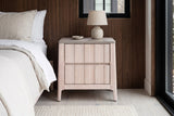 Calangianus whitewash nightstand with a ceramic lamp against dark walnut wood panelling in a Nashville bedroom with a pale grey-washed oak floor and an ivory wool rug