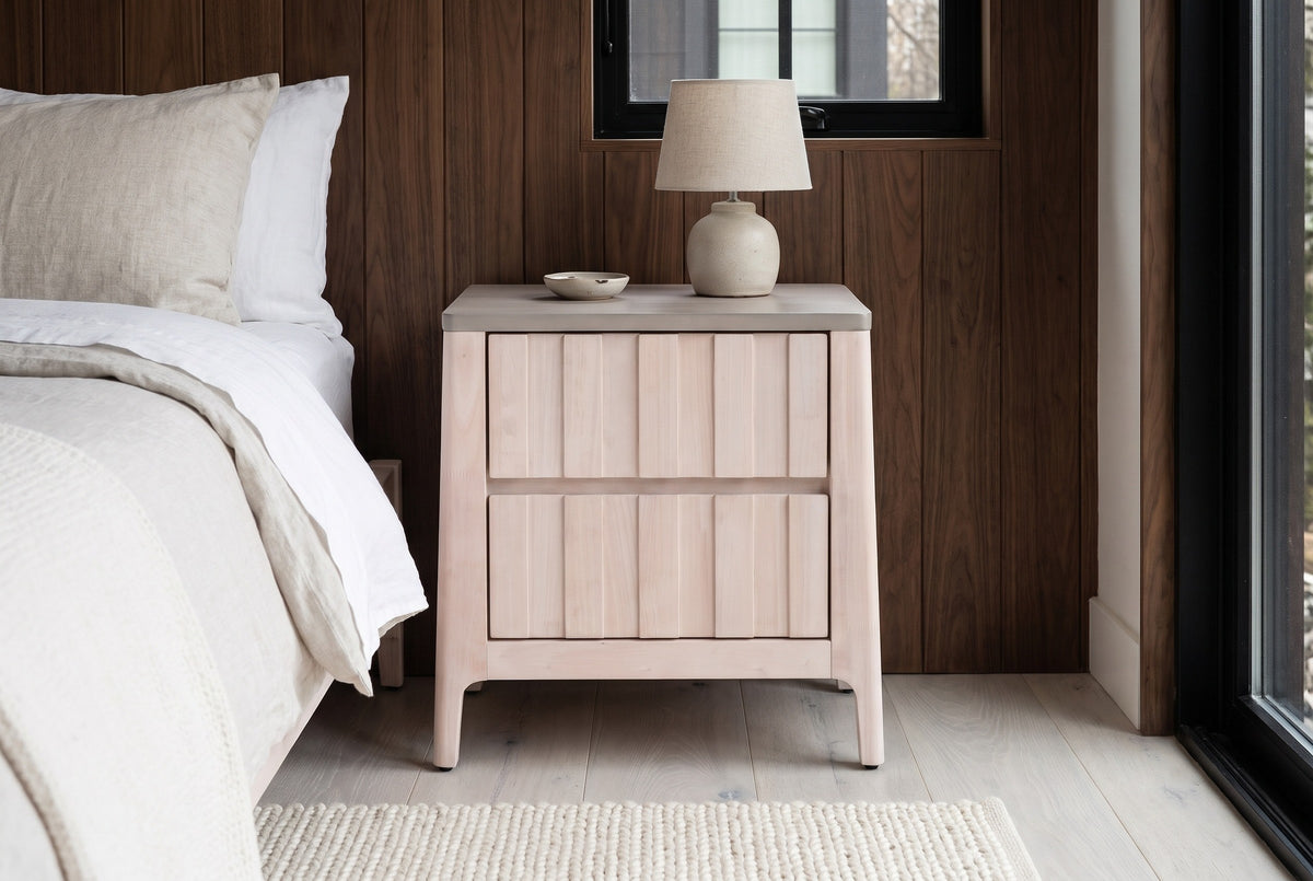 Calangianus whitewash nightstand with a ceramic lamp against dark walnut wood panelling in a Nashville bedroom with a pale grey-washed oak floor and an ivory wool rug