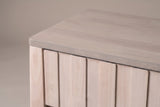 The top drawer of the Calangianus nightstand: narrow vertical planks with no handle, beside the rounded corner of the grey-washed top