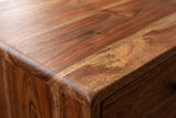 Close-up of the chestnut mango wood on the Calasetta nightstand: reddish brown grain with golden streaks running to a rounded edge