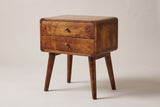 The Calasetta two-drawer nightstand in chestnut mango with brass knobs, rounded corners and four splayed round legs, three-quarter view on a light studio backdrop