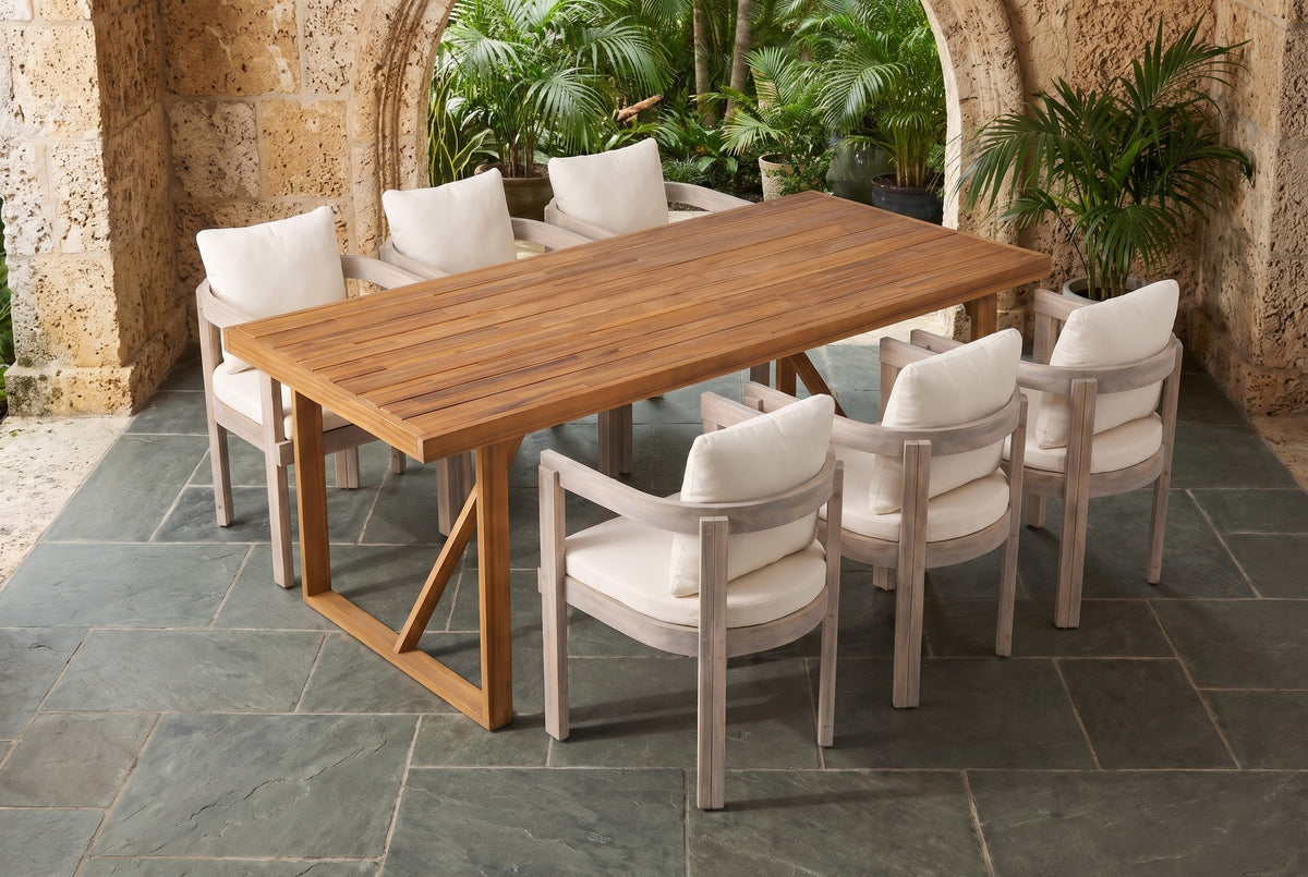Caltagirone acacia dining set in a Coral Gables loggia with coral-rock walls, a wide arch onto a tropical garden and a slate flagstone floor (planters not included)