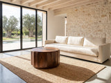 Camaiore Faceted Mango Drum Coffee Table on a jute rug in front of a linen sofa in a poolside villa