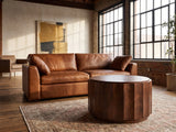 Camaiore Faceted Mango Drum Coffee Table on a vintage rug in front of a leather sofa in an industrial loft