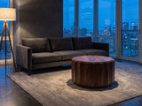 Camaiore Faceted Mango Drum Coffee Table on a wool rug in front of a velvet sofa in a city penthouse at blue hour