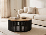 Camogli Mango and Black Metal Drum Coffee Table styled with books, a vase and a stone bowl in front of a cream sofa in a bright plaster room