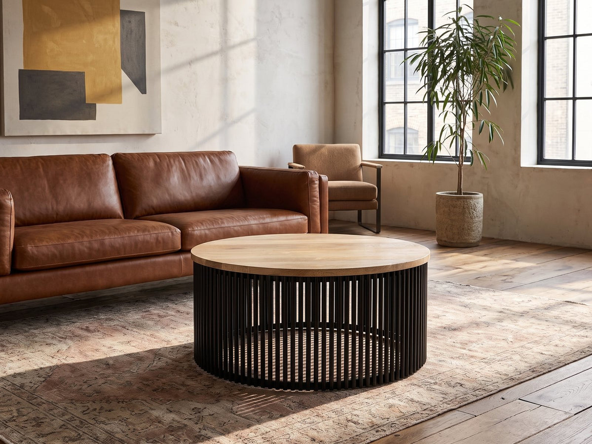 Camogli Mango and Black Metal Drum Coffee Table on a vintage rug in front of a leather sofa in an industrial loft