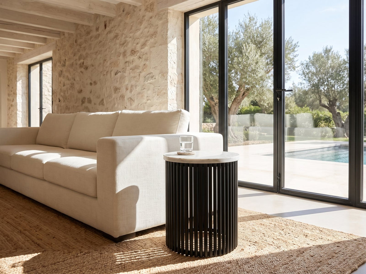 Camogli Marble and Black Metal Drum Side Table beside a linen sofa in a poolside villa