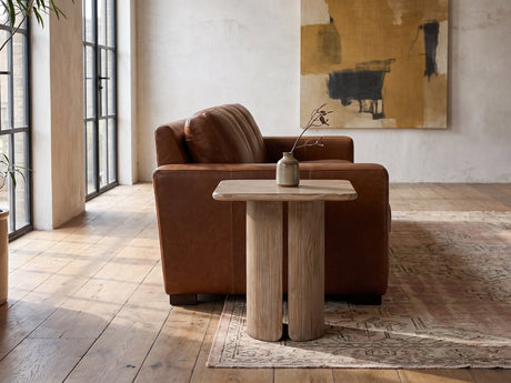 Campli Reclaimed Pine Split Pedestal Side Table beside a cognac leather armchair in an industrial loft