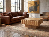 Canelli 31-Inch Square Scalloped Ash Veneer Lift-Top Coffee Table on a vintage rug in front of a leather sofa in an industrial loft