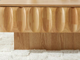 Close-up of the Canelli 31-Inch Square Scalloped Ash Veneer Lift-Top Coffee Table: the carved scoops of the solid wood band above the recessed plinth