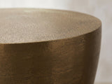 Close-up of the Capestrano Antique Brass Cast Aluminum Drum Side Table: the crisp rim of the top over the curved brass body