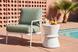 Capizzi concrete side table on terracotta tiles by a pool in Palm Springs, a pink breeze-block wall and a fan palm behind, beside a white lounge chair with a sage cushion (chair and decor not included)