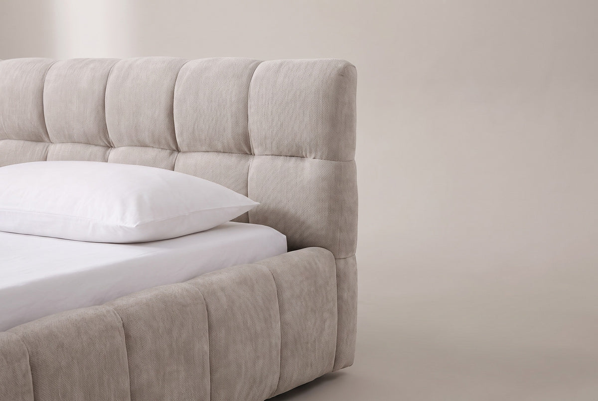 One end of the Capracotta headboard: two rows of plump square beige chenille biscuits above a white pillow