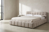 Capracotta beige chenille floor bed against a white limewash plaster wall in a Los Angeles bedroom, a tall black steel window at the left