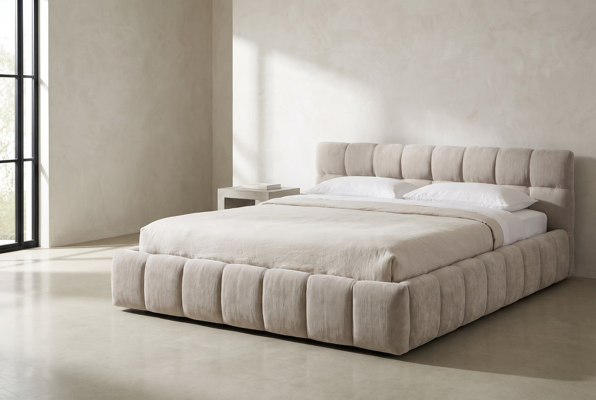 Capracotta beige chenille floor bed against a white limewash plaster wall in a Los Angeles bedroom, a tall black steel window at the left
