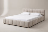 The Capracotta floor bed in beige chenille with a white mattress and pillows (not included), three-quarter view on a light studio backdrop