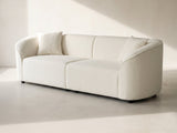 Capri Curved Boucle Sofa in ivory against a plaster wall in morning light