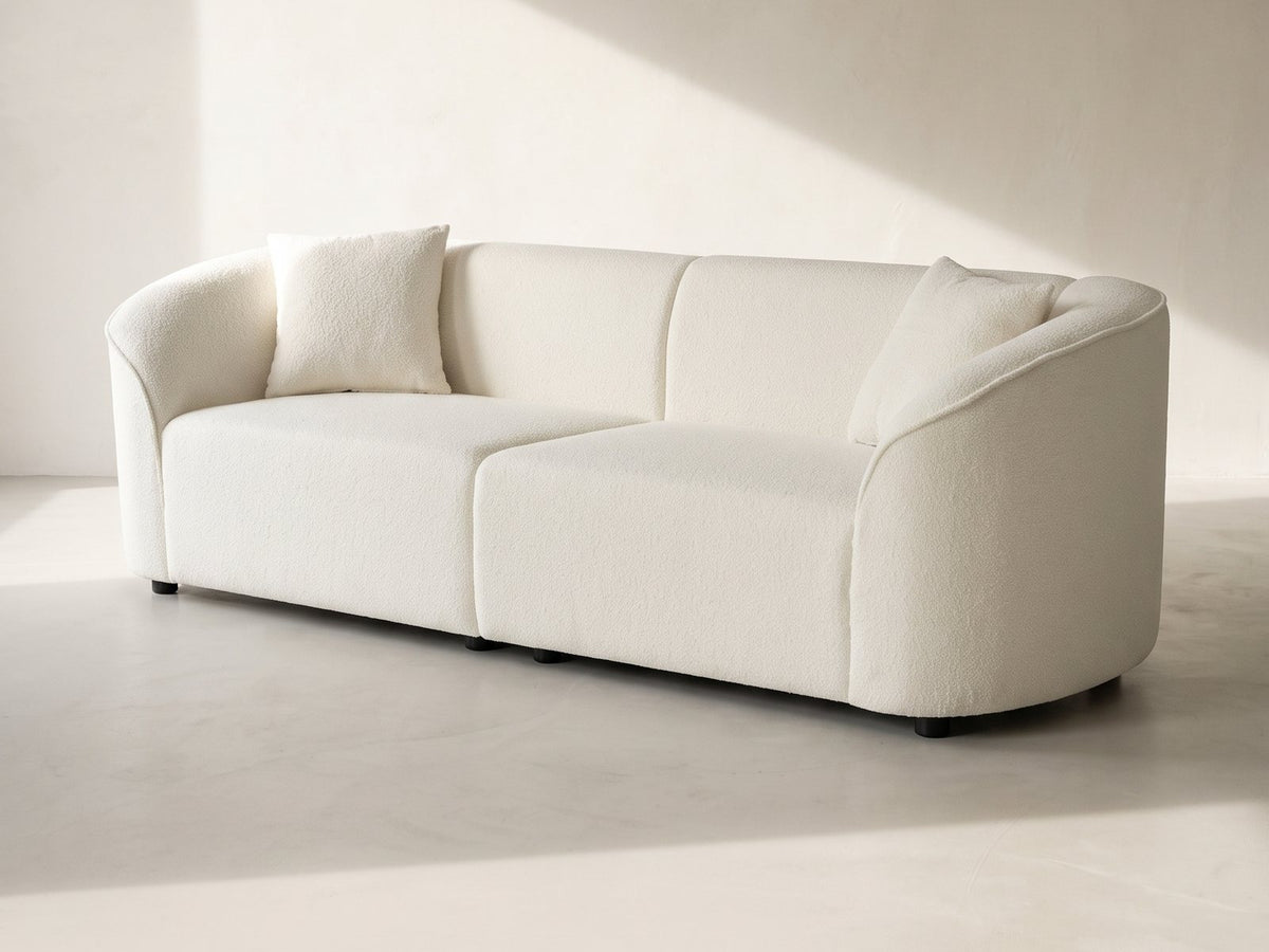 Capri Curved Boucle Sofa in ivory against a plaster wall in morning light