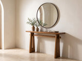 Capurso Wood Veneer Trestle Console Table under a round mirror in a travertine entryway