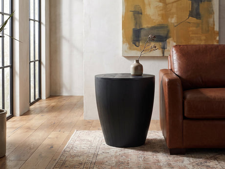Caramanico Black Mango Tapered Drum Side Table beside a leather sofa in an industrial loft