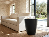 Caramanico Black Mango Tapered Drum Side Table beside a linen sofa in a poolside villa