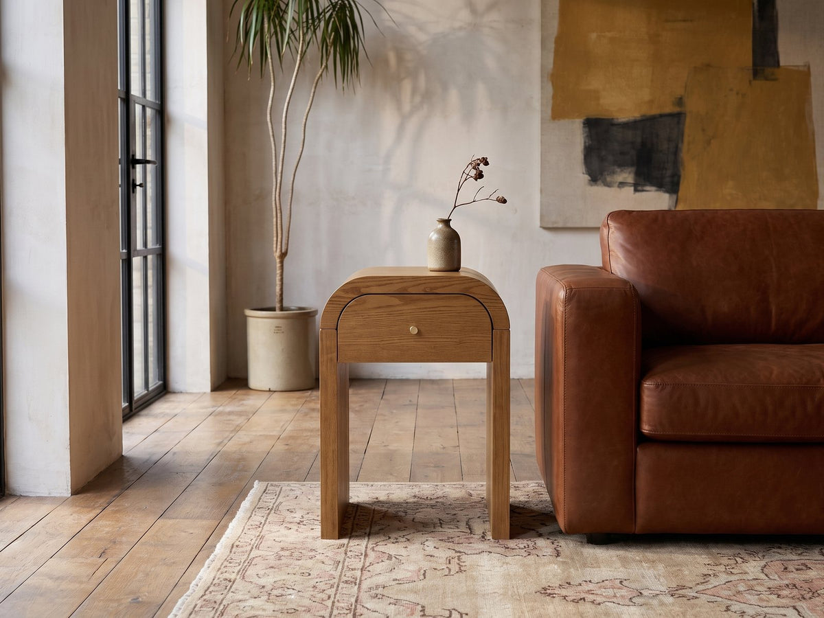 Cariati Ash Veneer Curved-Top Side Table beside a leather sofa in an industrial loft