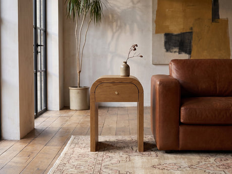Cariati Ash Veneer Curved-Top Side Table beside a leather sofa in an industrial loft