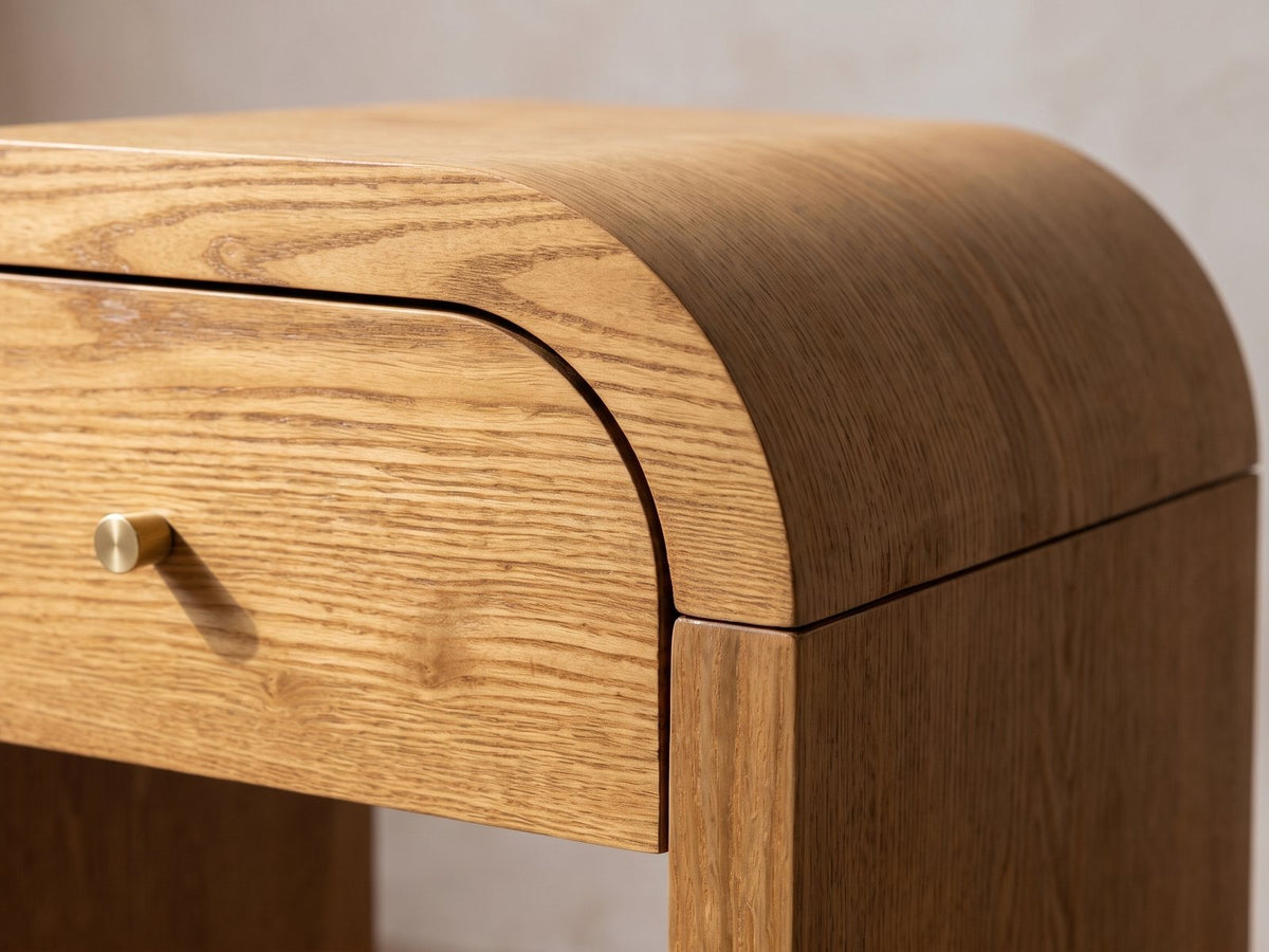 Close-up of the Cariati Ash Veneer Curved-Top Side Table: the rounded shoulder of the top over the drawer and gold-tone knob