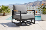 The Carini swivel glider lounge chair on a terrazzo pool patio in Palm Springs, a white breeze-block wall, a fan palm and the mountains behind (side table and drink not included)