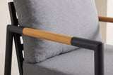 Close-up of the Carini arm: the teak wood sleeve with its fine grain, the black aluminum corner turning down into the front post and the gray cushions
