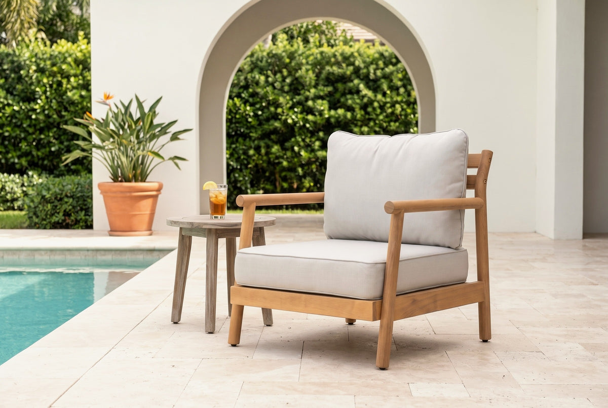 Caronia acacia club chair on a travertine pool deck in front of a white stucco wall with an arched opening and a clipped hedge (side table not included)