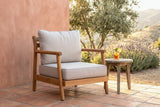 Caronia acacia club chair on a terracotta-tiled terrace against a pink lime-plaster wall at golden hour, an olive tree and lavender behind (side table not included)