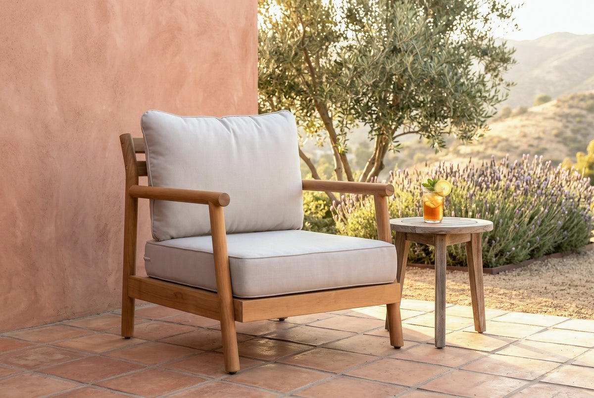 Caronia acacia club chair on a terracotta-tiled terrace against a pink lime-plaster wall at golden hour, an olive tree and lavender behind (side table not included)