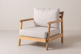 The Caronia acacia club chair with beige cushions, three-quarter front view on a light studio backdrop