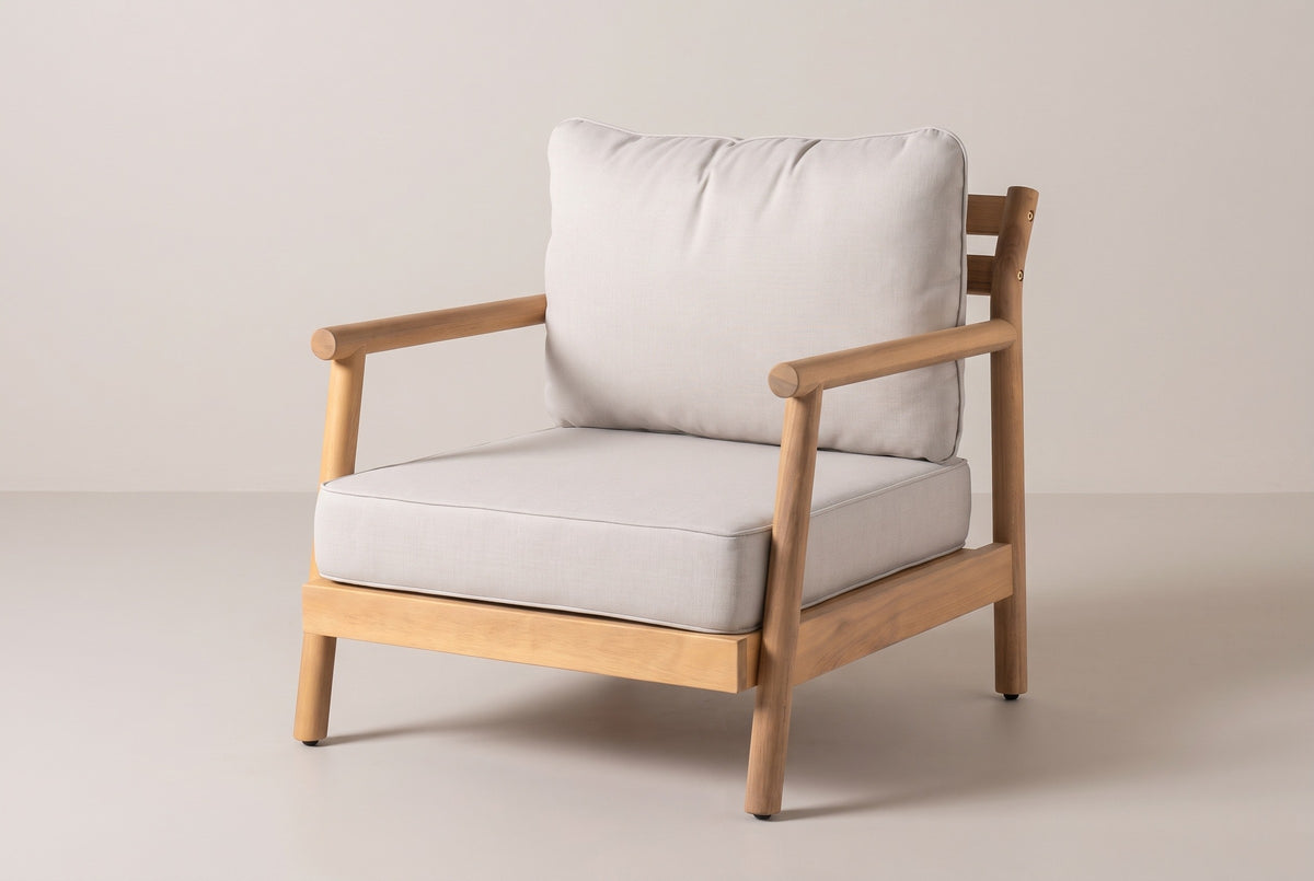 The Caronia acacia club chair with beige cushions, three-quarter front view on a light studio backdrop