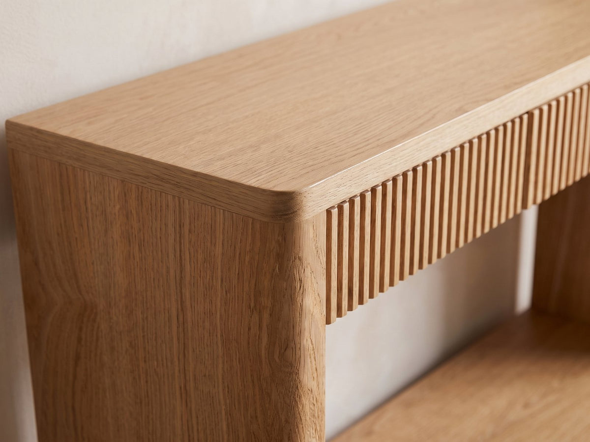 Close-up of the Carovigno Fluted Wood Veneer Console Table: the rounded corner of the frame beside the slatted front of the left drawer