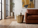 Carovilli Hammered Metal Drum Side Table beside a leather sofa in an industrial loft