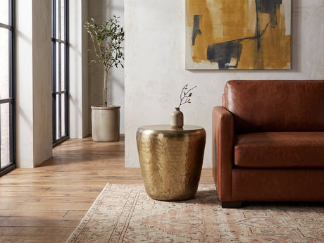 Carovilli Hammered Metal Drum Side Table beside a leather sofa in an industrial loft