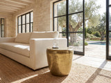 Carovilli Hammered Metal Drum Side Table beside a linen sofa in a poolside villa