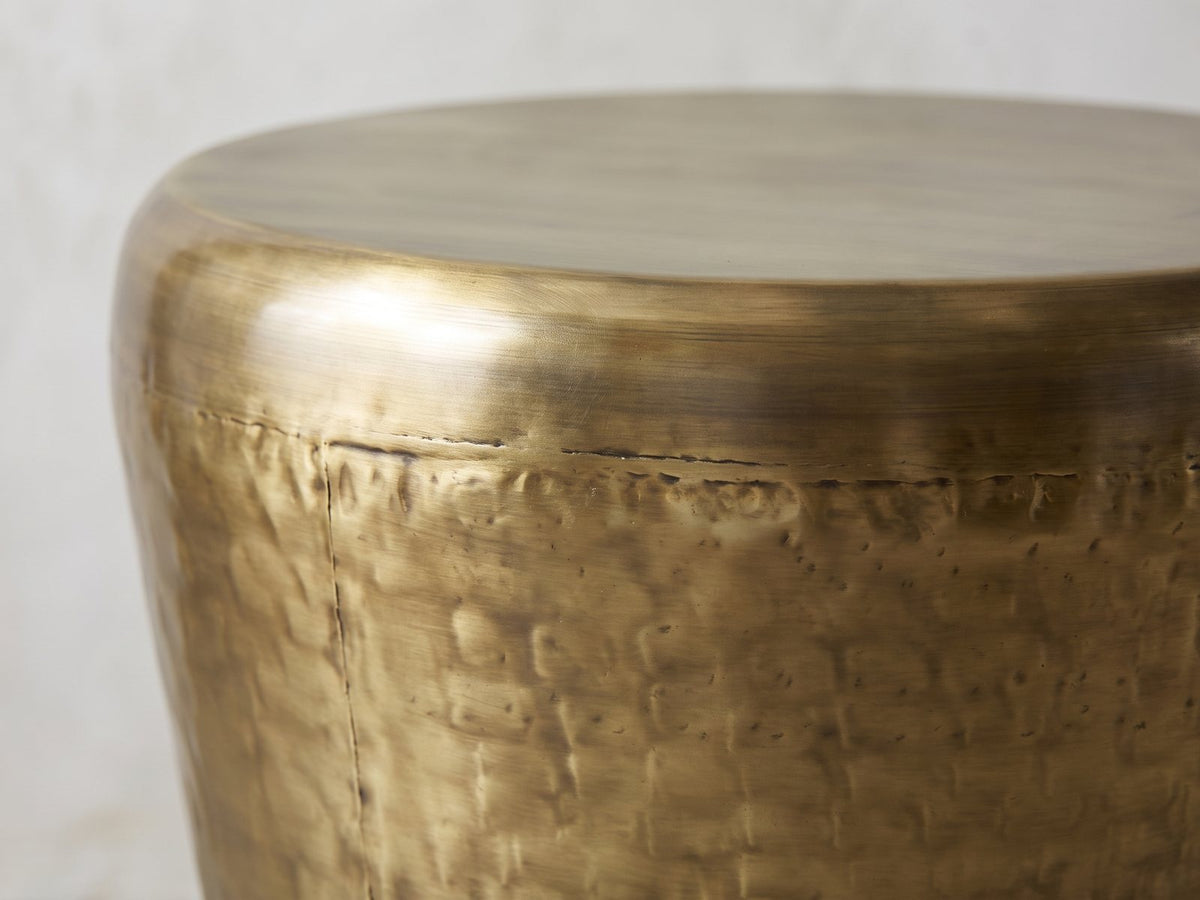 Close-up of the Carovilli Hammered Metal Drum Side Table: the rolled rim of the top over the hammered body